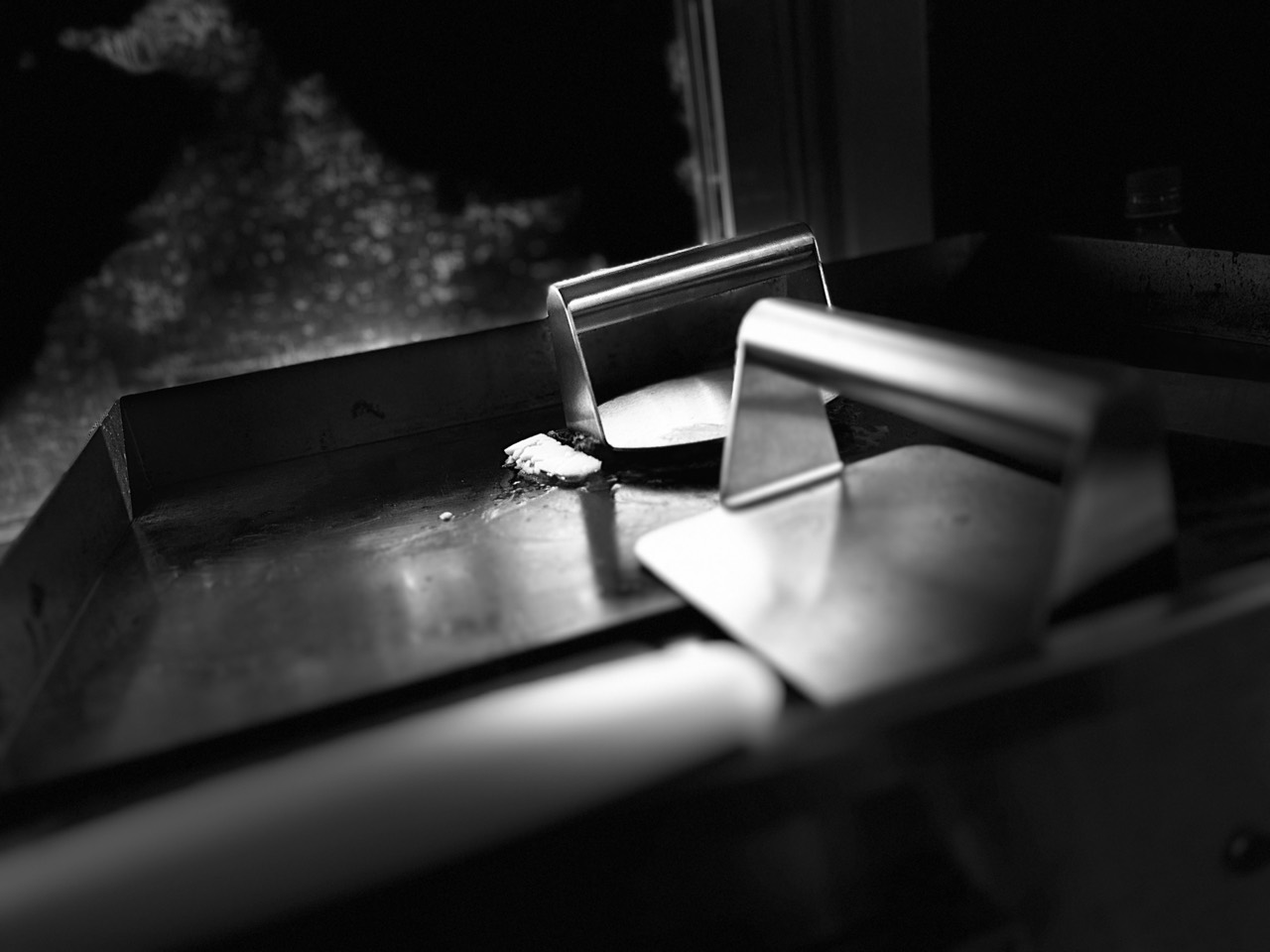 A bench scraper resting on a steel prep counter